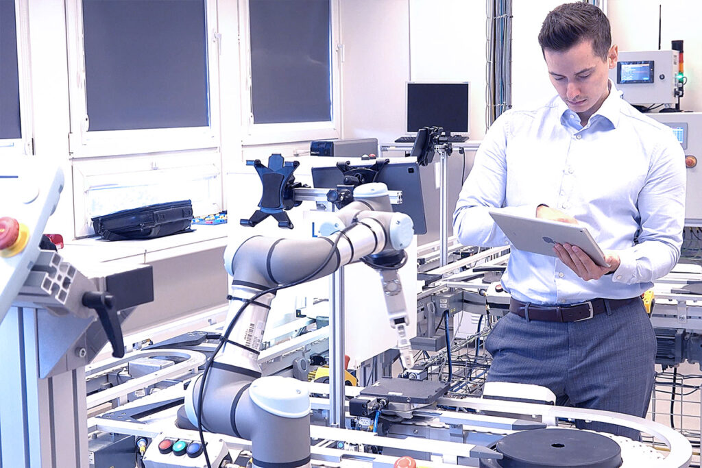 Specialist using a tablet beside a collaborative robot on a production line